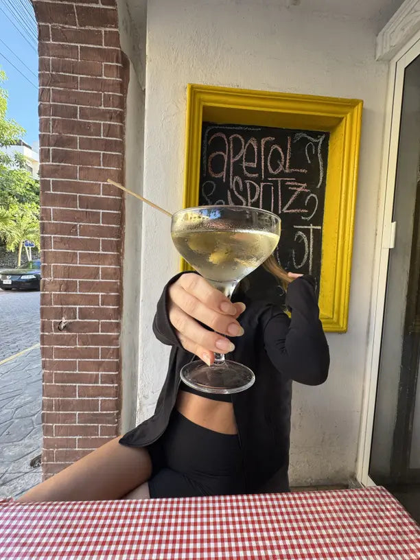 woman in black holding a dirty martini over a red table cloth