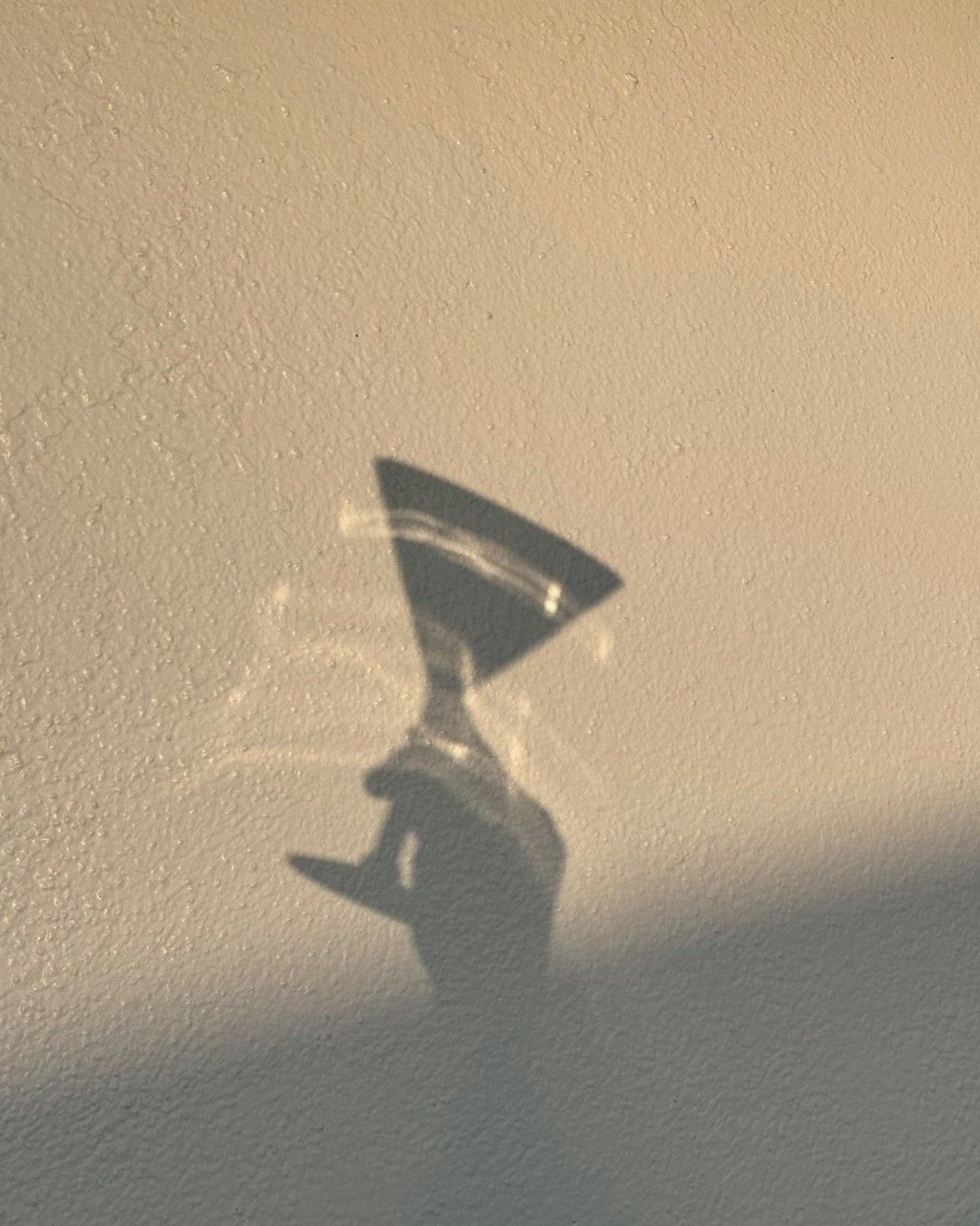 shadow of a la saum martini glass against a white wall