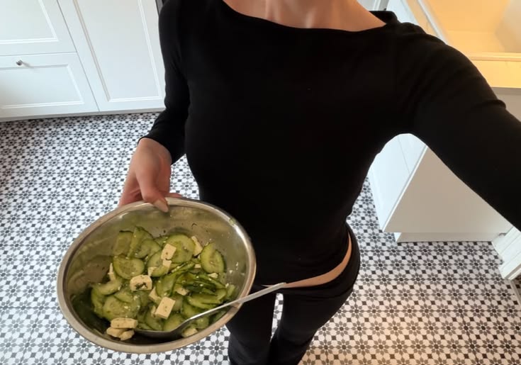 girl in black shirt holding a bowl of salad with la saum dressing
