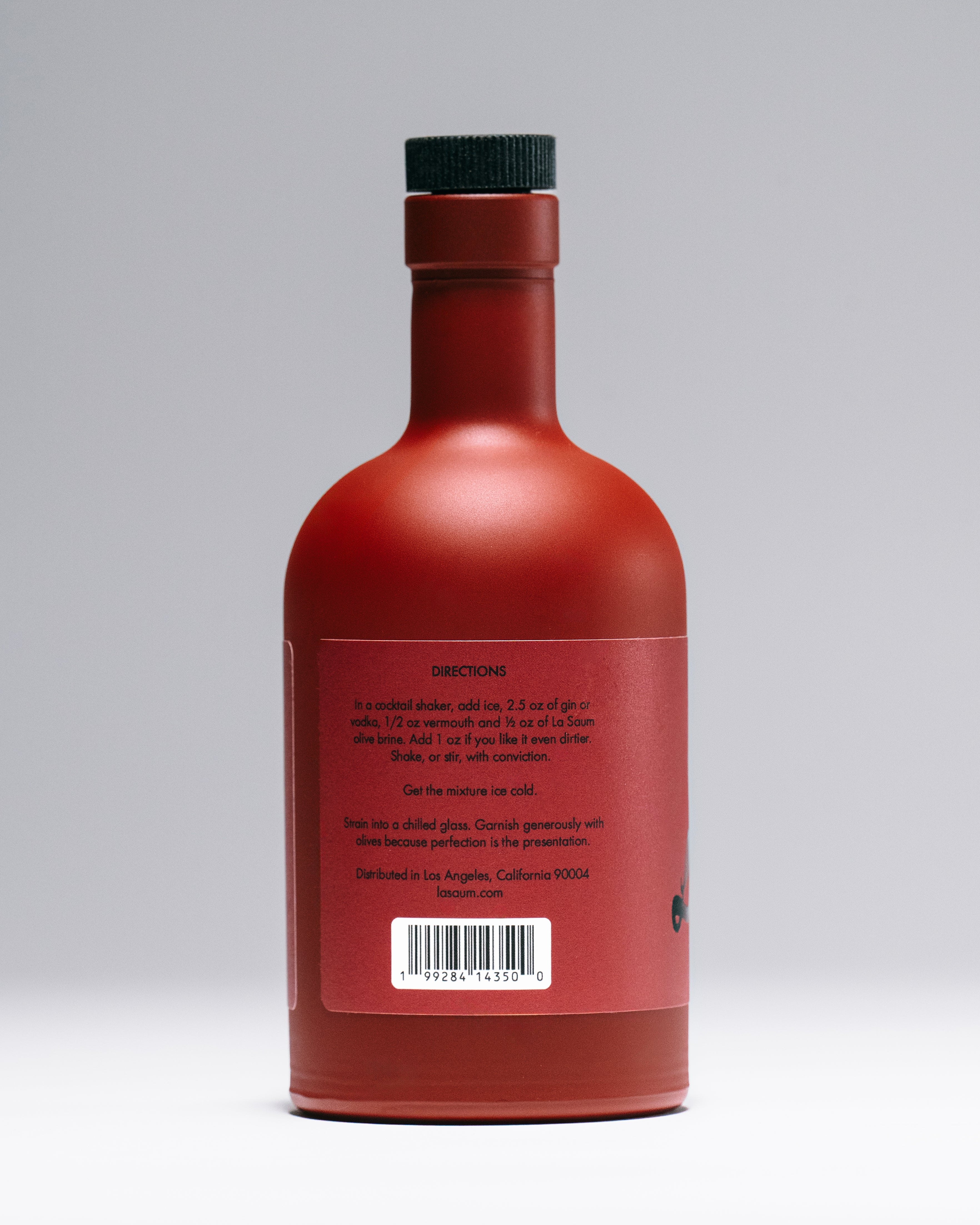 La Saum Red bottle with black cap on a gray background