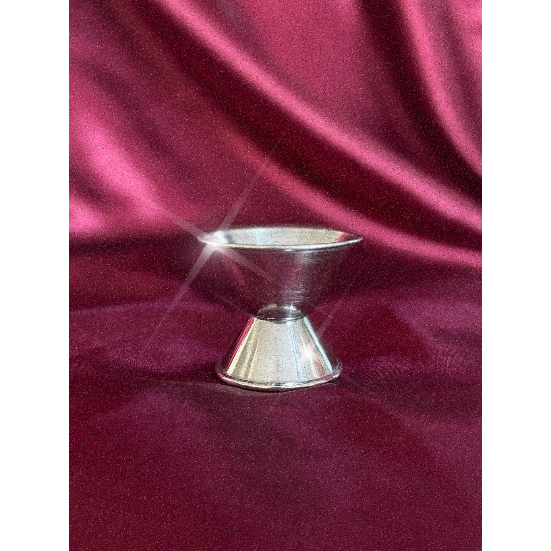 Silver jigger on a red fabric background